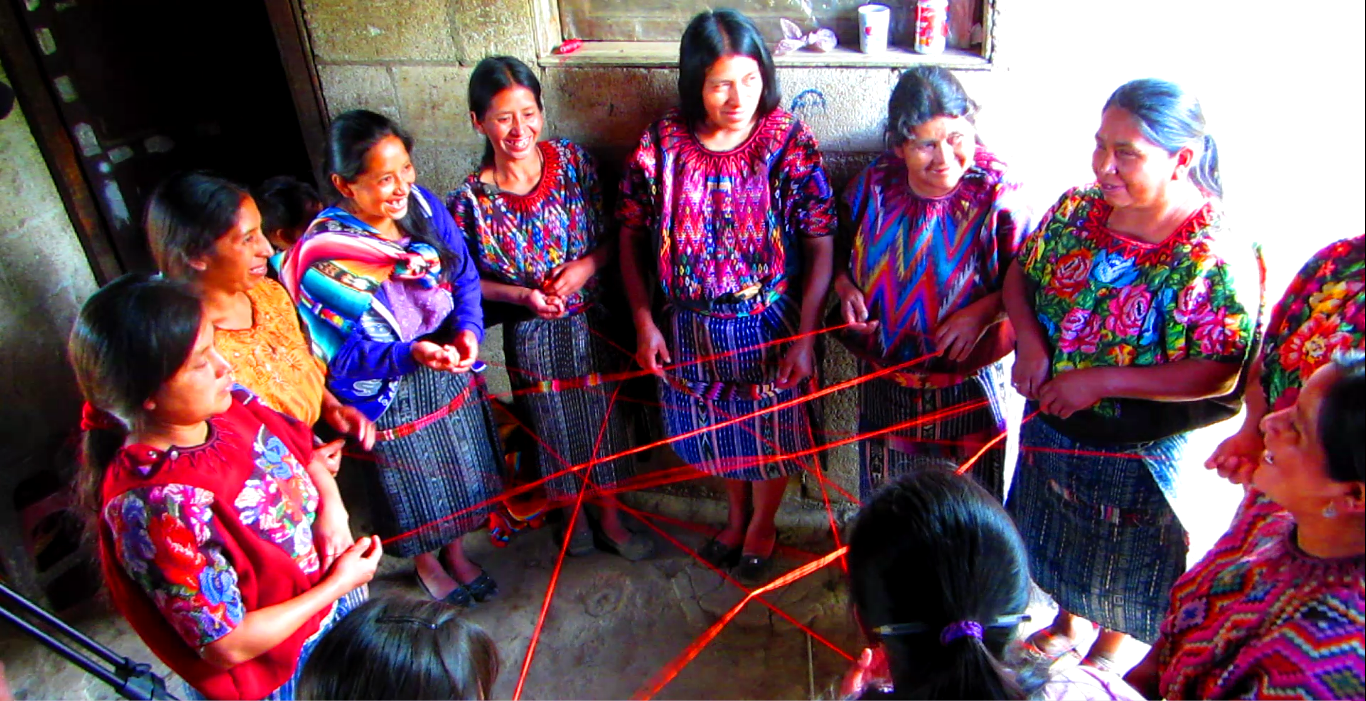 "Here a solidarity group / trust bank from the MFI, Friendship Bridge learns about solidarity. In this interactive dynamic borrowers pass ball of yarn in the group, where each member introduces themselves and their respective business. Once the yarn has been passed completely around the circle, the Loan Officer asks the members to describe what they notice. A web has been created and if one member drops their piece of yarn, the whole web gets tangled. In the same way, a solidarity group lending model is dependent on trust and teamwork."