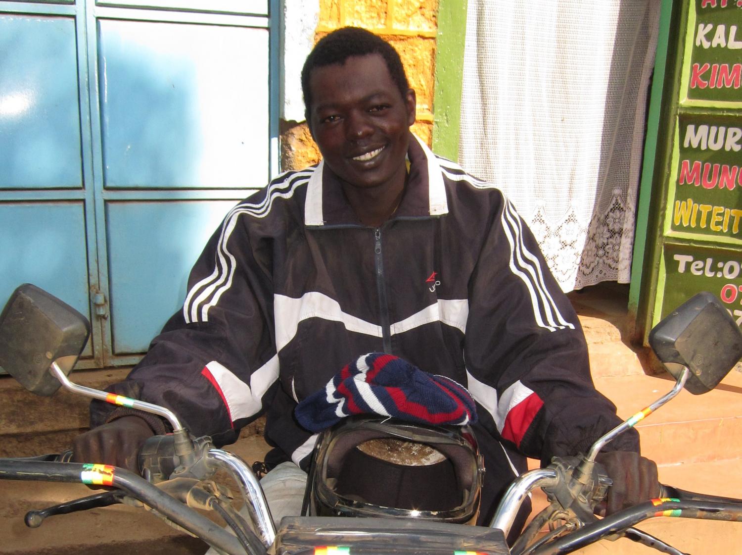 Joseph with the piki piki he purchased with a Kiva loan.