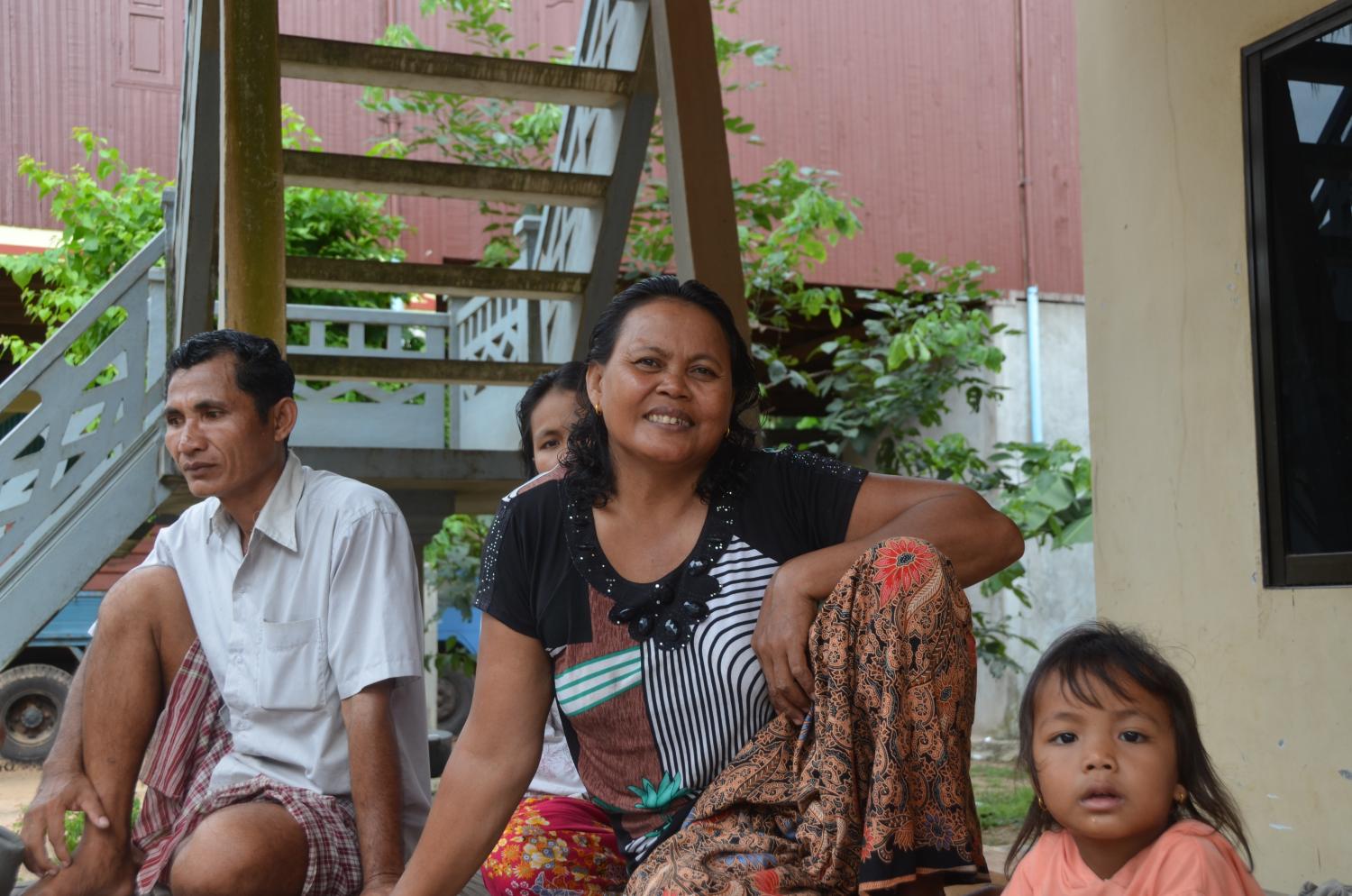 Kiva borrower Nom with her family. Loans to purchase fertilizer for her rice and cassava crops have enabled her to expand her farmland, improve her house, and produce rice wine to sell for cooking.