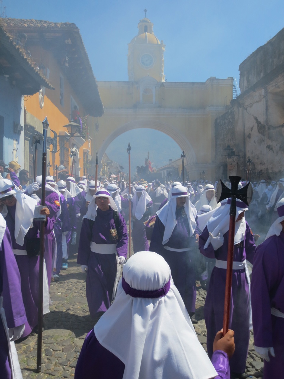 A procession arrives in the distance amidst smoke from burning incense