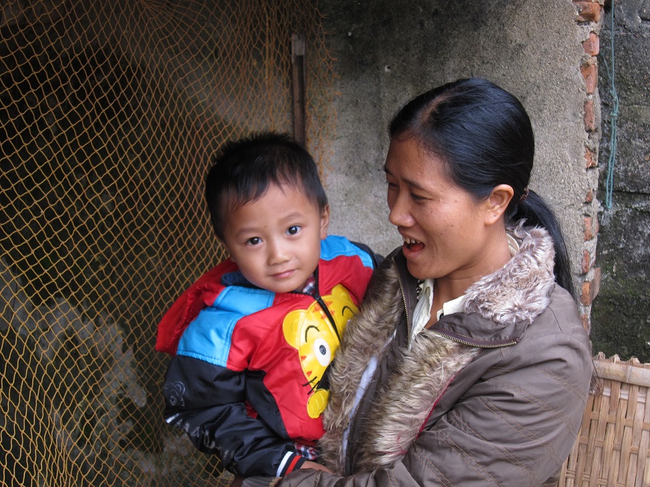 FPW borrower, Dung, with one of her children at her home in the central Vietnamese province of Thanh Hoa. With her Kiva loan, Dung was able to buy chicks to raise in her chicken coop, as well as a motorbike-washing machine. She is constantly thinking of new ways to diversify her income to support her family (opening a beverage stand is next on her list), which makes it easy to see why her peers elected her to lead their solidarity group. Jon Fung, Vietnam.