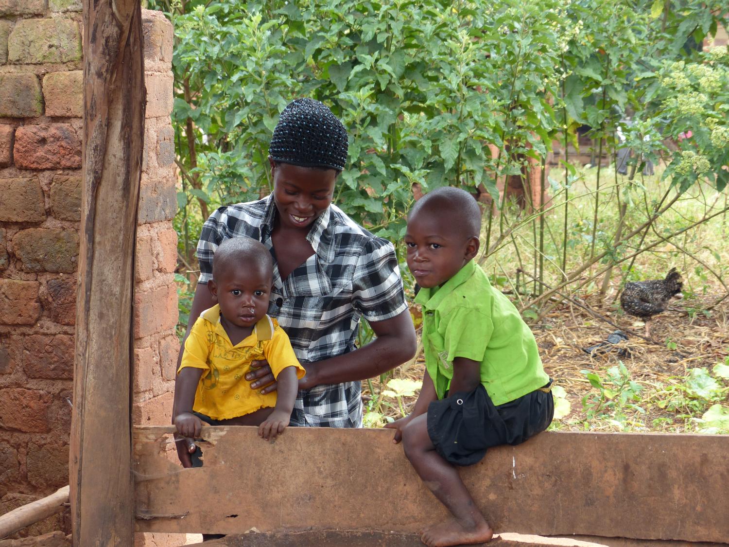Grameen Foundation borrower, Alice, with two of her sons in Buwama, Uganda, looking at their piglet named Kiva. Alice used the money she made from her work as a Grameen Community Knowledge Worker to purchase the piglet. Additional income pays school fees for her 4 boys. Her dream is to one day be an agricultural specialist. Katie Krummel, Uganda