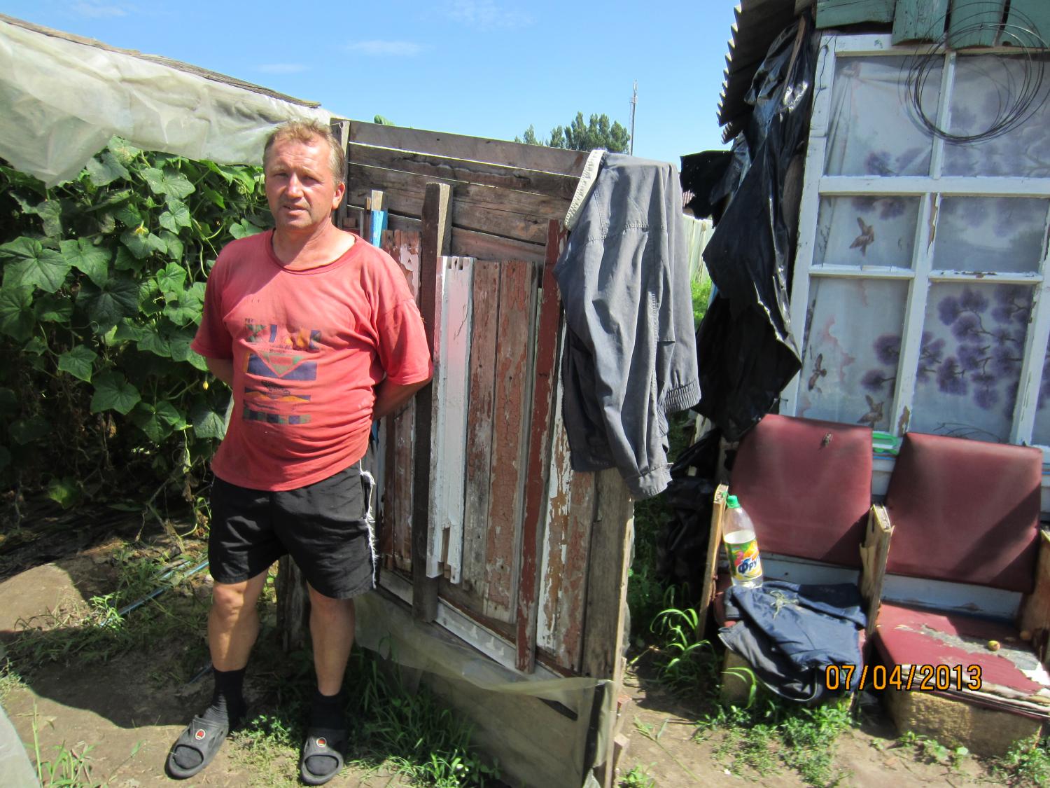 This is Mikhail. The shack next to him holds a new heating system for his greenhouse, purchased with a Kiva loan.