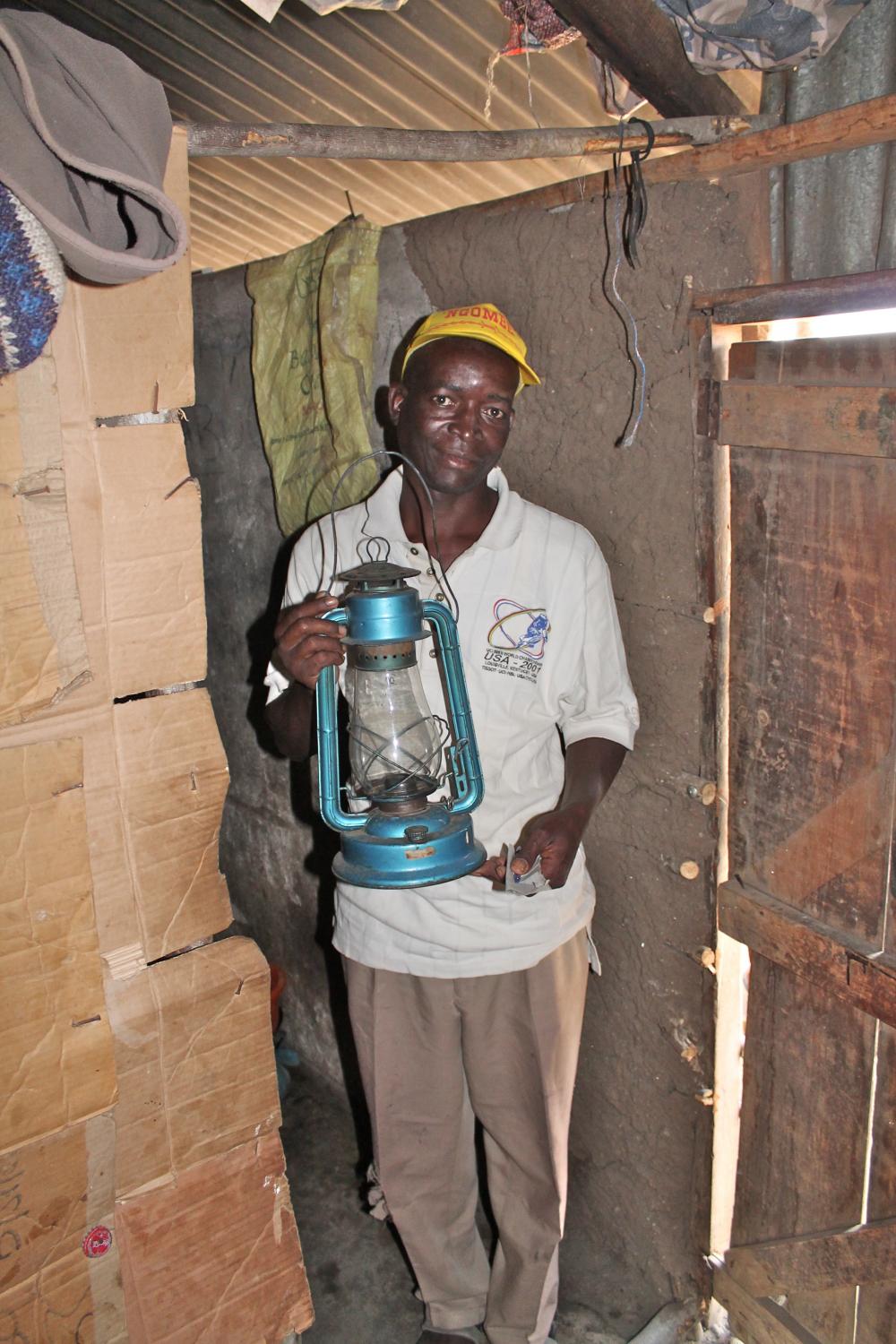 Kenneth inside his "hotel"with a kerosene lantern.