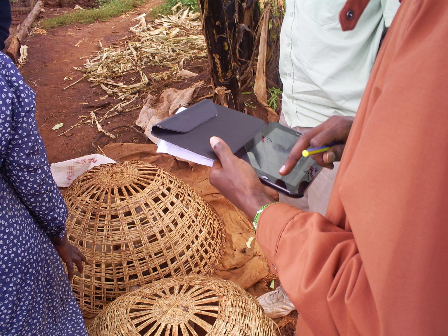 A Juhudi Kilimo Credit Officer using a tablet in the middle of Kenya's unpaved heartland.