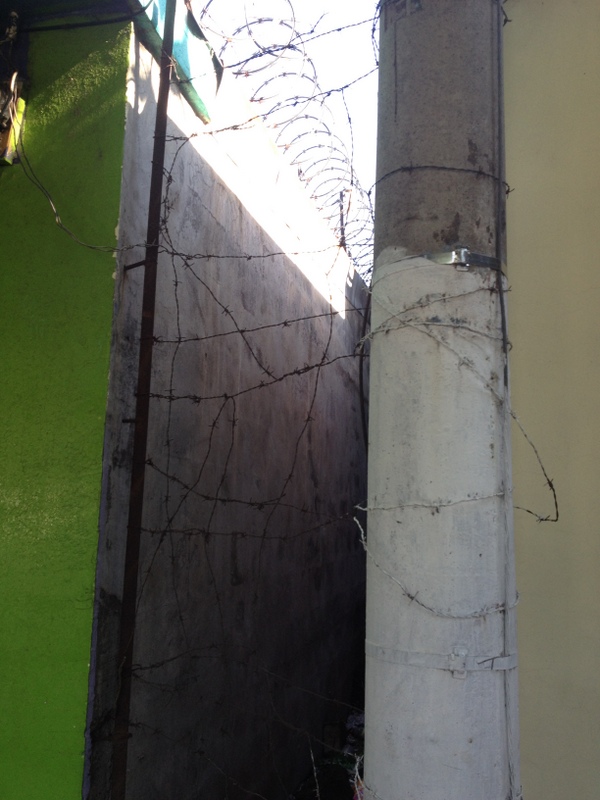 Barbed wire guarding the alleyway and the roof above. Unfortunately its necessary to deter crime.
