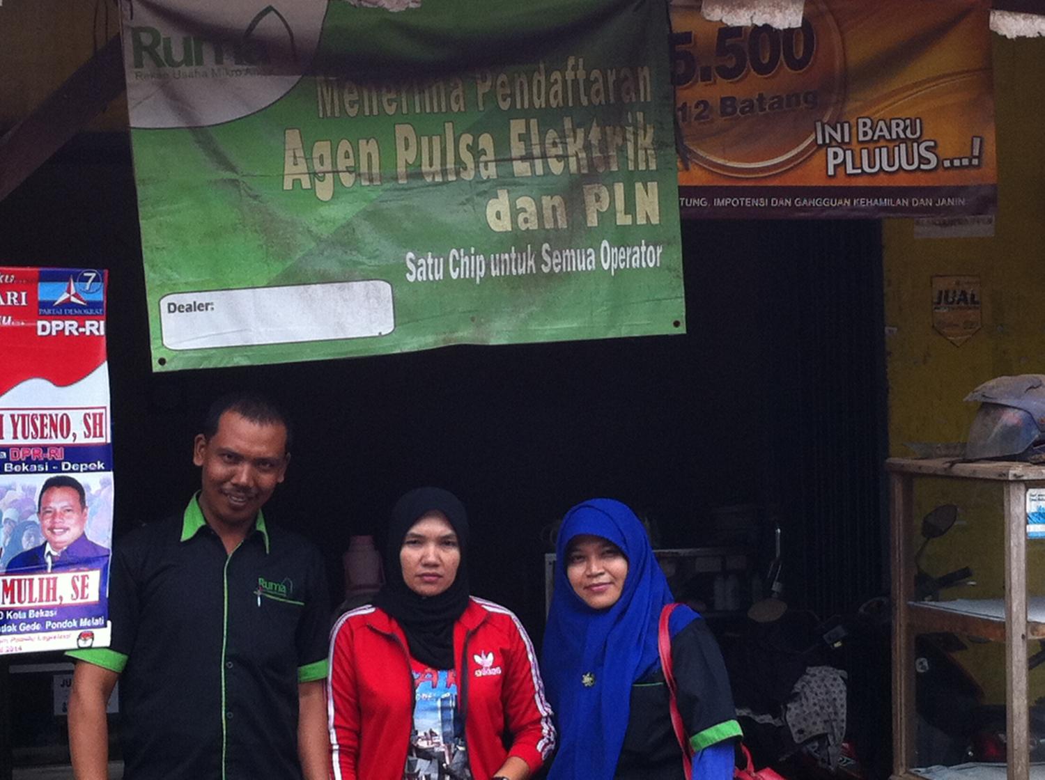 A Ruma agent posing with field officers in front of her warung