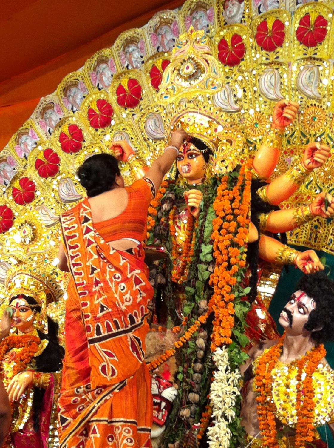 A woman puts sindur on Durga