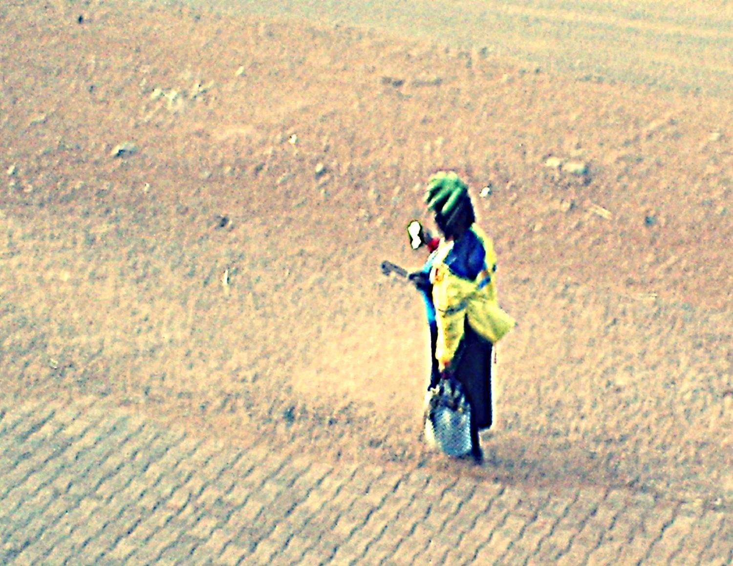 Memorable African Moment: A woman walking home in Kakamega carrying a bag, umbrella under her arm, plantains on her head, and....a smartphone in hand.