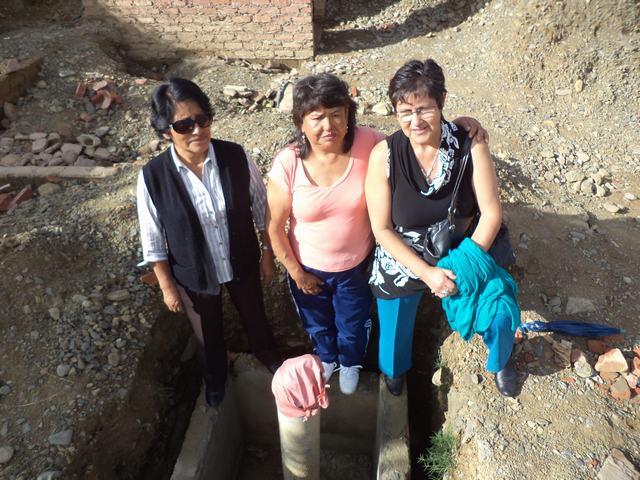 Three representatives of the Cochabamba Loan Board standing at the site of the new well