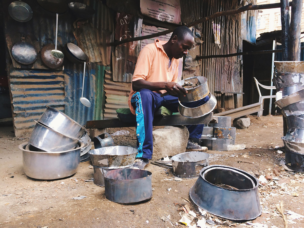 Caleb, a metal worker in Nairobi, Kenya, shows Kiva Fellow Tiffany Vlaanderen the variety of products he makes.
